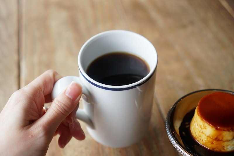 Cafe Tococheのコーヒーを手に持っている様子