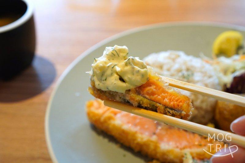 「CAFE & RESTAURANT ORGALI(オーガリ)」のレアサーモンフライを箸で持ち上げている様子
