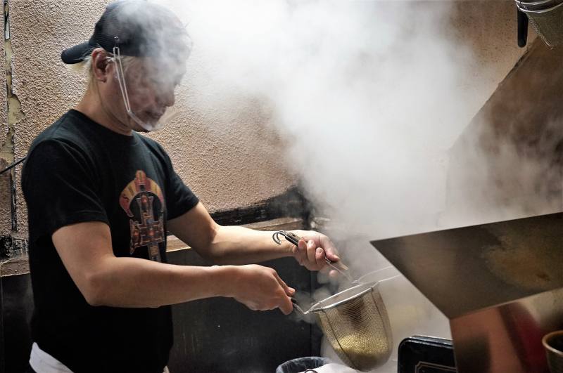 麺やすずらんの店主 鈴木さんが、ラーメンの湯切りをしている様子