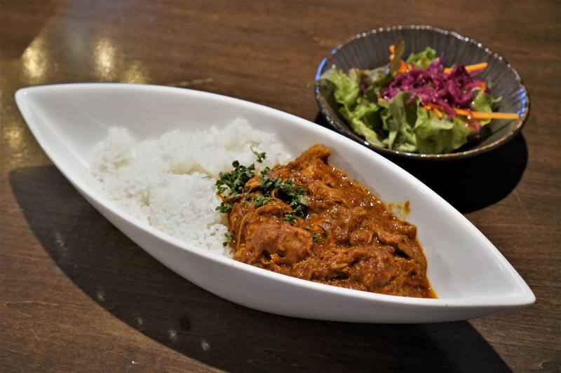 肉専門店本気のスパイスチキンカレーとサラダがテーブルに置かれている