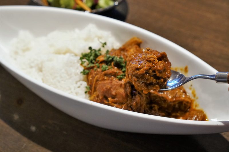 ほろほろに煮込まれた鶏肉がたっぷり入ったカレーを、スプーンですくっている様子