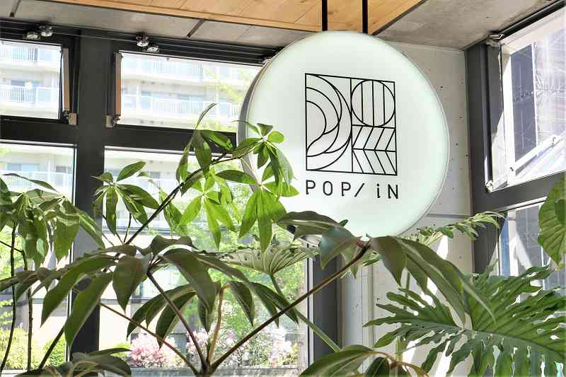 モノトーンのシンプルな「POP/iN（ポップイン）」の看板が天井からつるされている