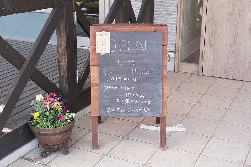 「おむすびcafe粒」の営業時間看板が地面に置かれている