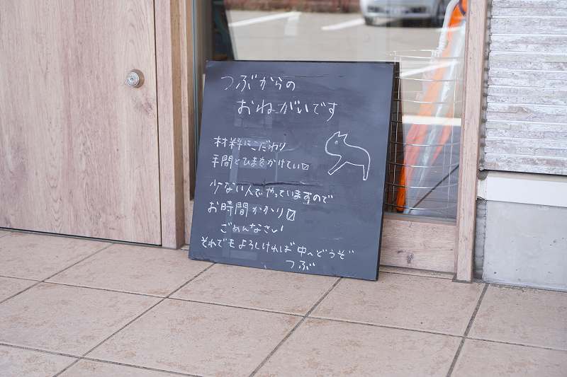 「おむすびcafe粒」のお願い看板が地面に置かれている