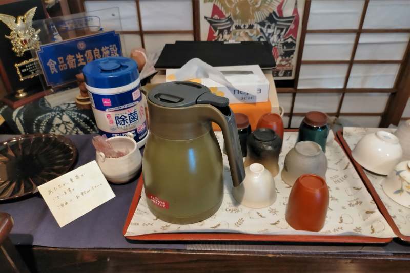 あたたかい麦茶が入ったポットと湯飲みがテーブルに置かれている