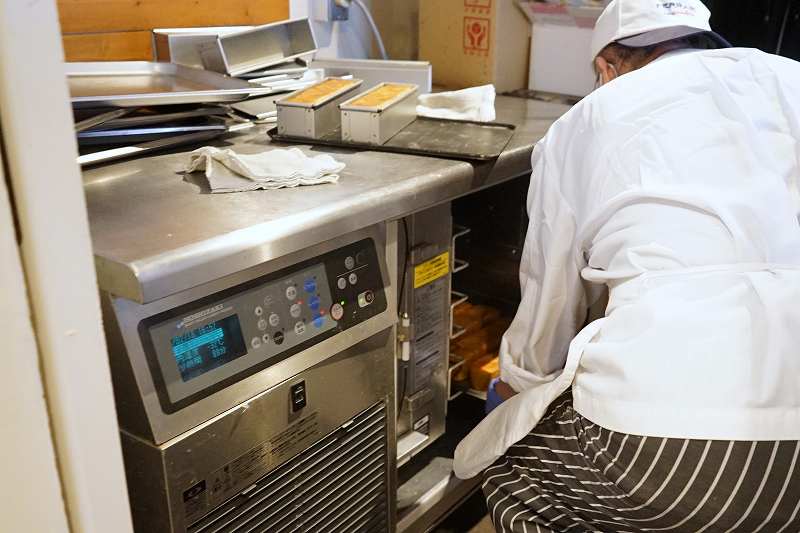 焼きあがった高級食パンを冷凍庫に入れている様子