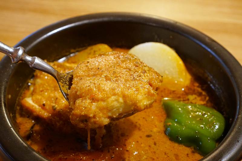 スプカレーのチキンをスプーンですくっている様子