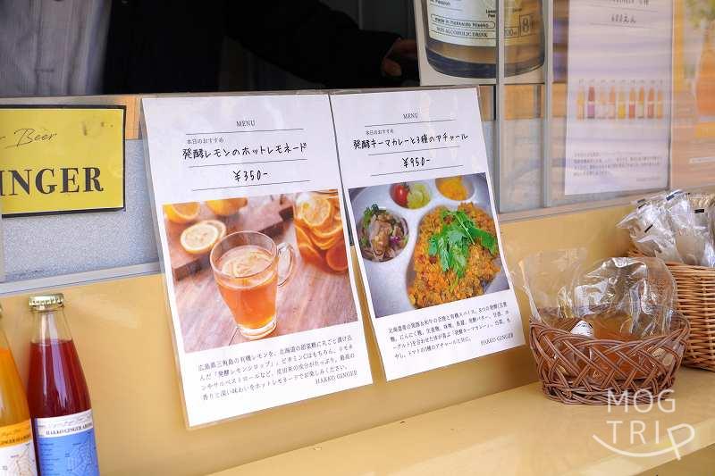 ハッコウキッチン桑園の「発酵レモンのホットレモネード」と「発酵キーマカレー」のメニューがキッチンカーに貼られている