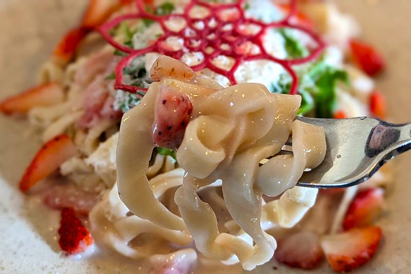 札幌にある「自家製生パスタと旬菜イタリアンagio（アジオ）」のいちごのクリームソースパスタを、フォークで持ち上げている様子